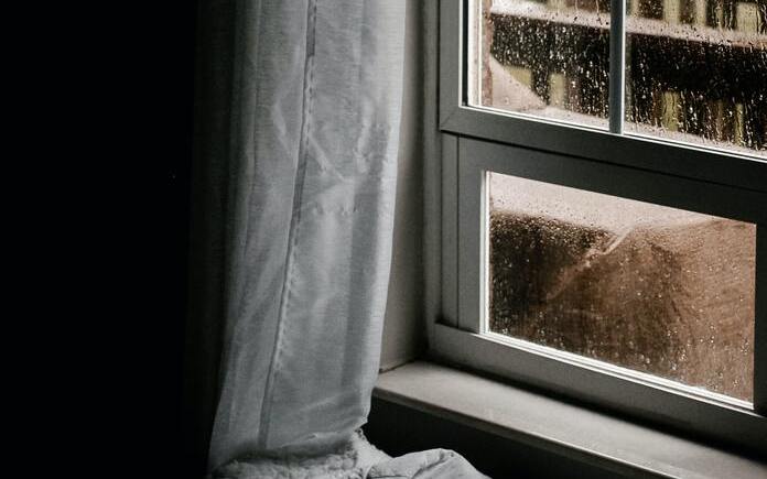 Water droplets on a window in a dark room.