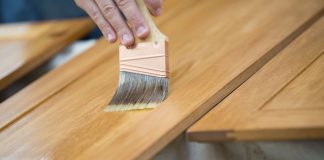 Paintbrush staining a wooden cabinet