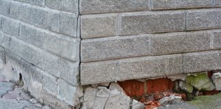 A grey brick foundation of a home is crumbling and needs repair.