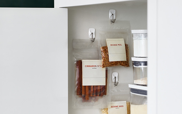 Command Wire Hooks with hanging cooking ingredients in a kitchen cabinet