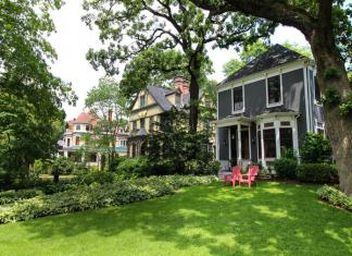 A home in Chicago with a large green front yard and red lawn chairs.