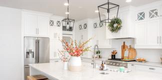 A white kitchen with white counter and pink flowers.