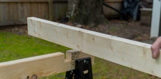 A 2x4 being slotted into a sawhorse to steady plywood.