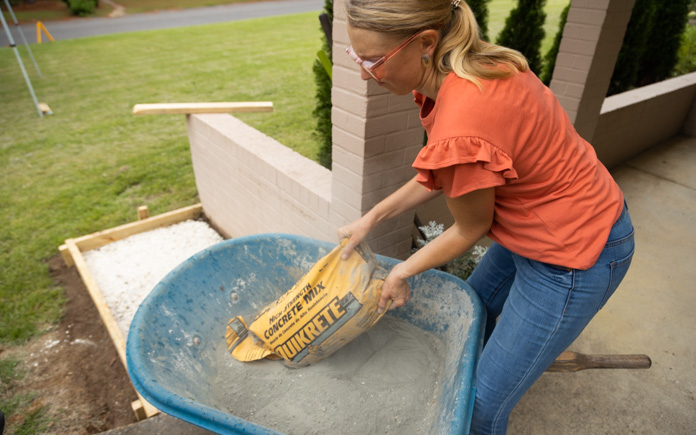 Chelsea Lipford Wolf pouring Quikrete concrete mix into wheelbarrow.