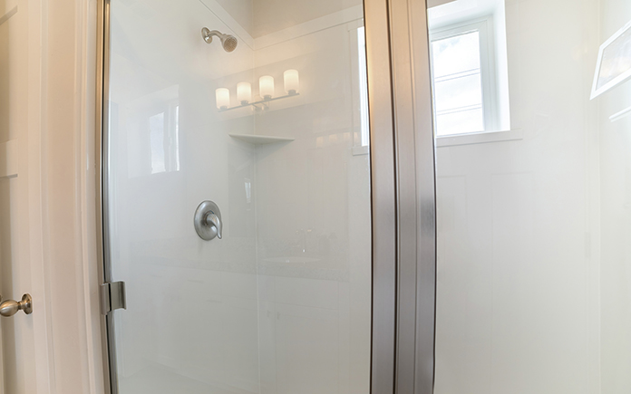 A fiberglass shower stall with glass panels and stainless steel frames.