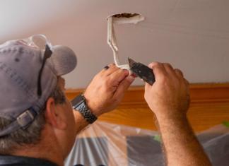 Man strips electrical wiring while installing a recessed light