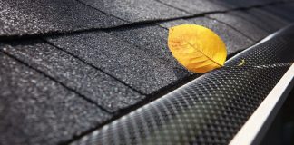 a closeup shot of a gutter guard with a yellow leaf on the outside
