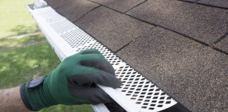 A close up shot of a person putting a guard on the gutter with a glove on