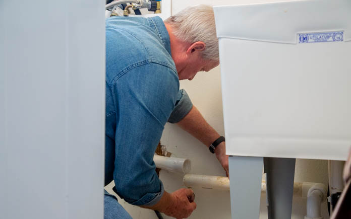 Danny fixes PVC pipe behind sink