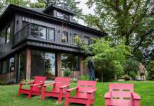 Stunning Portland, Oregon home with metal roof, seen from the backyard, with red lounging chairs on the grass.