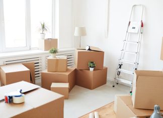 A room with white walls and window lighting with cardboard moving boxes stacked around