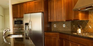 Closeup photo of a walkway behind Kitchen Island with stainless steel appliances, gas stove, stone counter tops and cherry wood cabinets with hardwood floors