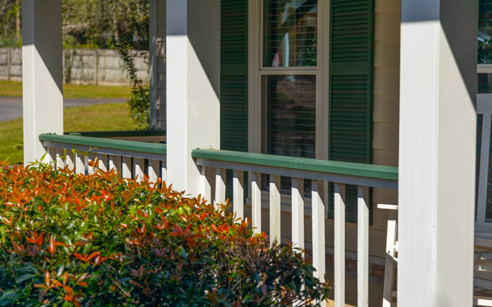 White front porch railing with green top rail