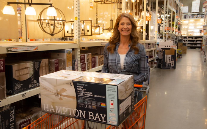Jodi Marks with the Hampton Bay Fanelee Smart Color Changing Ceiling Fan in a shopping cart in Home Depot.