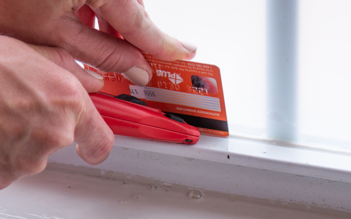 Cutting a straight line on a window with a box cutter and a plastic card