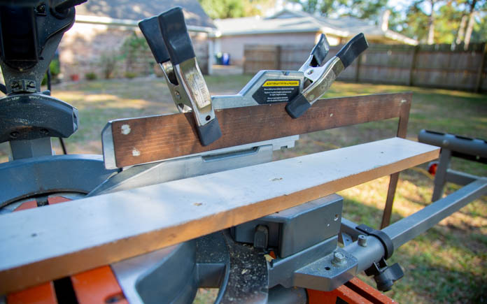 A framing square clamped to a miter saw as a stop block.
