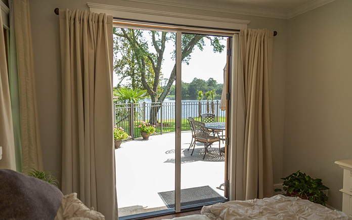Sliding glass door in a bedroom overlooking a waterfront.