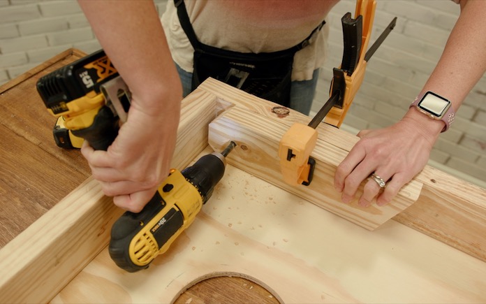 Drilling a leg onto the underside of a cornhole game board.