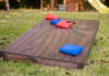 A cornhole game board with red and blue bags