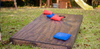 A cornhole game board with red and blue bags