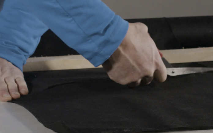 Man's hand with scissors cutting black fabric