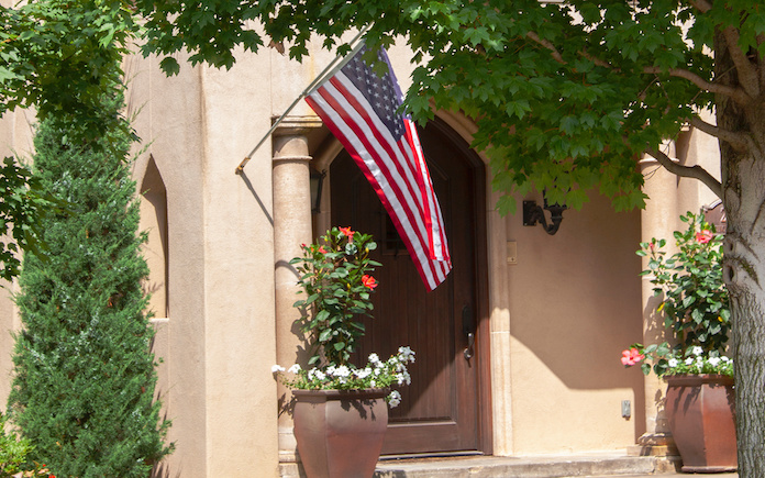 An American flag flying from a flag holder on a stucco home.