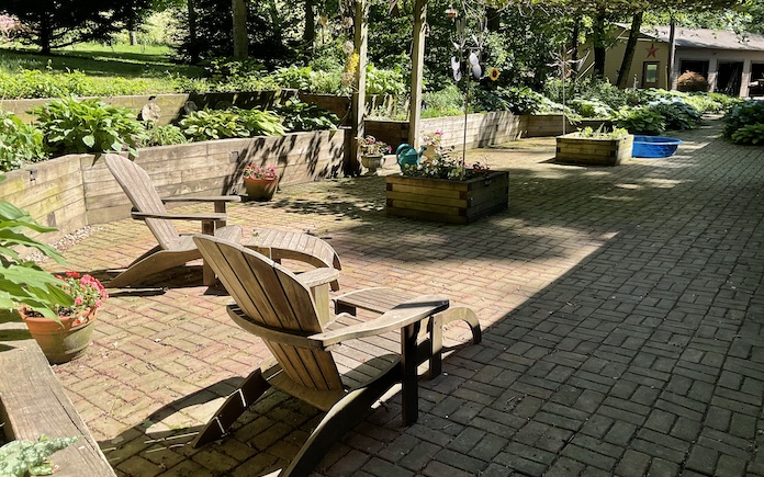 Brick paver patio with raised planter boxes and Adirondack chairs