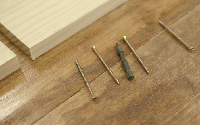 Trim screws and a countersink drill bit  next to a wood board