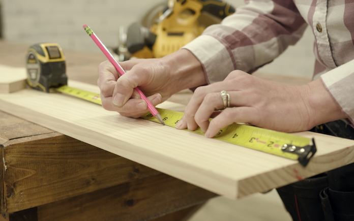 Measuring a board with a tape measure.