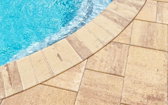 Stone paver pool coping next to stone tile