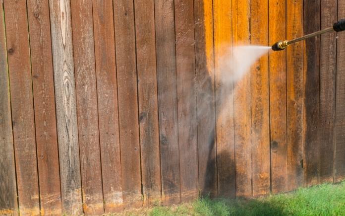 Pressure washing a wood fence for summer home maintenance