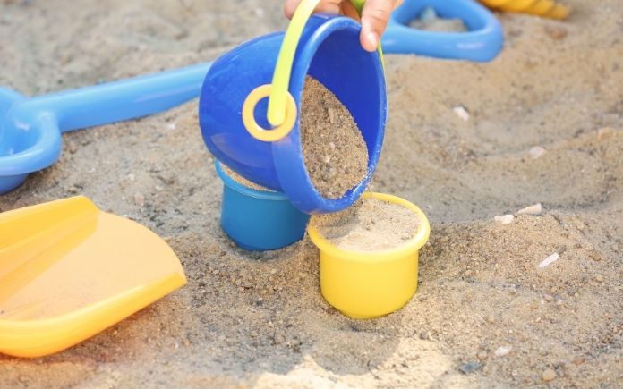filling toy buckets with sand in a children's sandbox