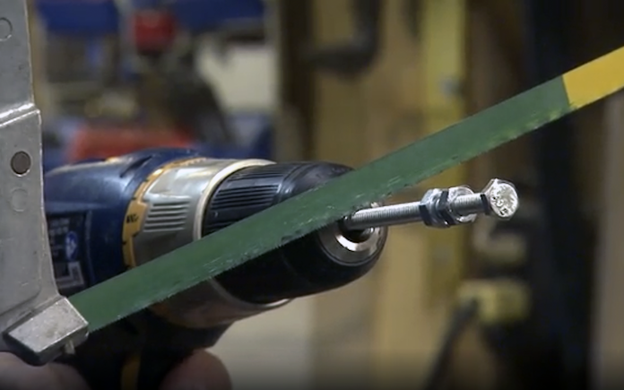 A hacksaw cutting a bolt in a drill