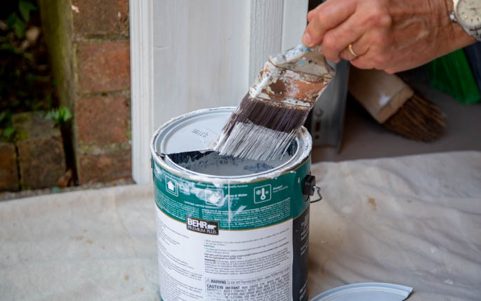 Paint cans with lids cut in half to prevent paint from dripping off the brush.