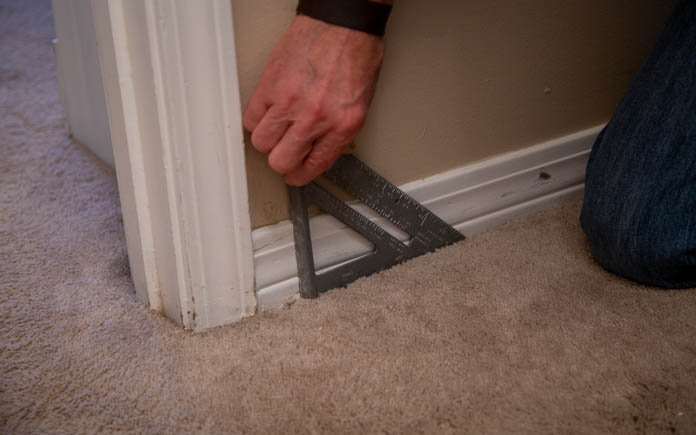 A speed square lined up along baseboard trim