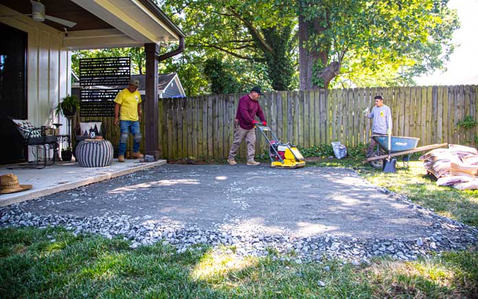 Worker uses compacter to compact paver base for a patio