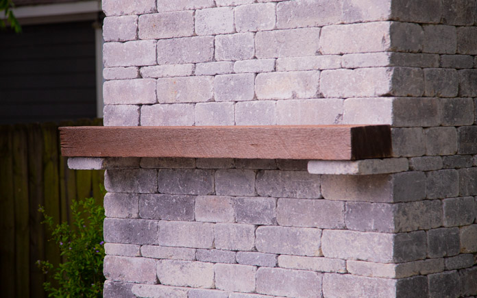 Wood mantel on a Pavestone Rumblestone outdoor fireplace