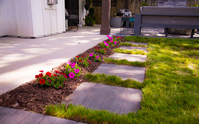 Stepping patio stones next to a concrete slab and flower border