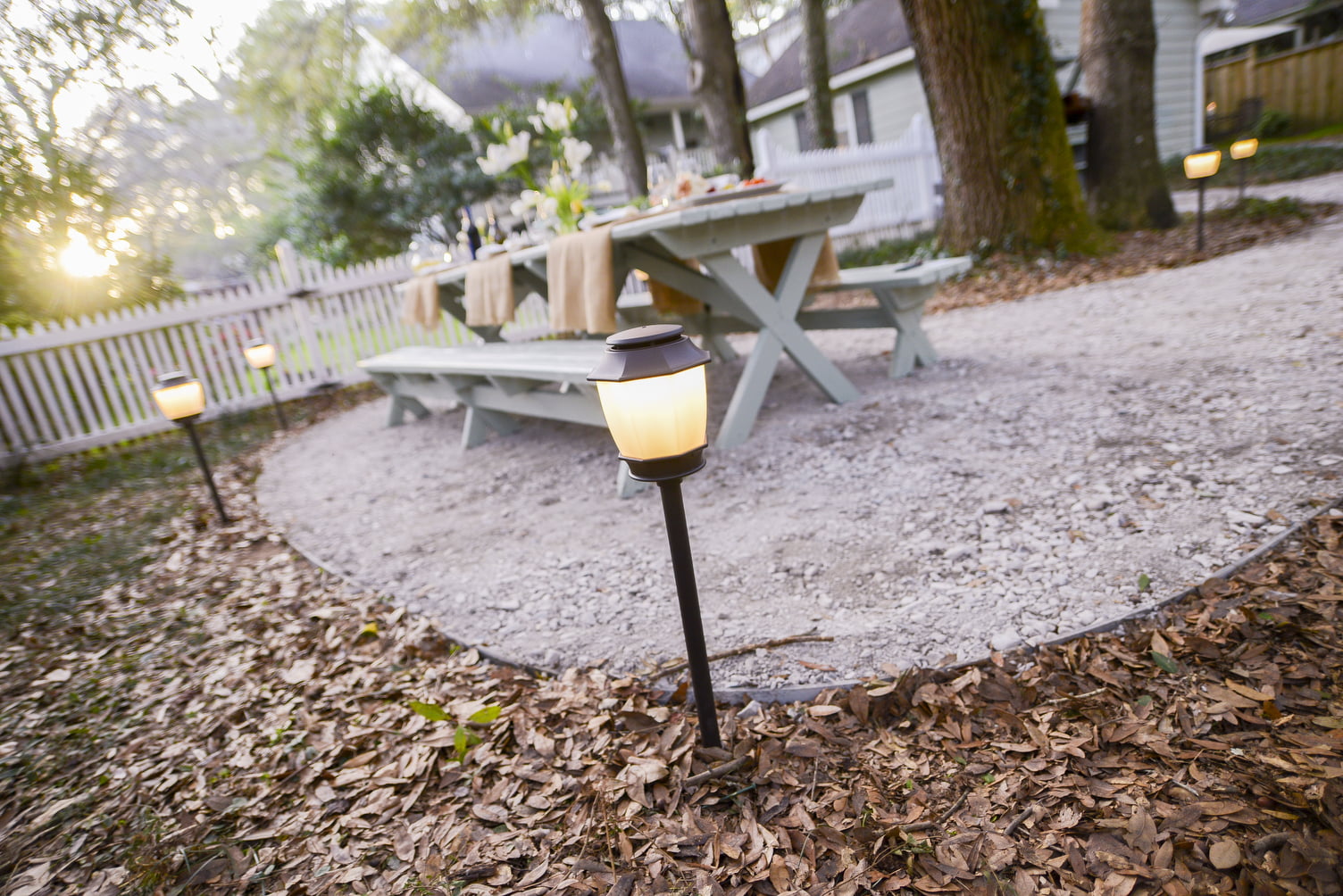 A picnic table on a paver base outdoor surface surrounded by outdoor lighting