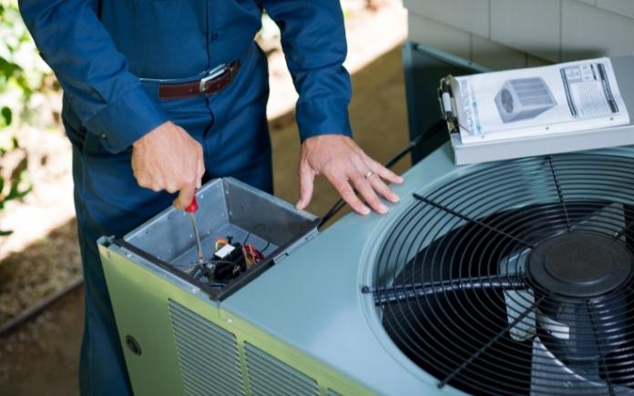 An A/C pro working on an air conditioner unit