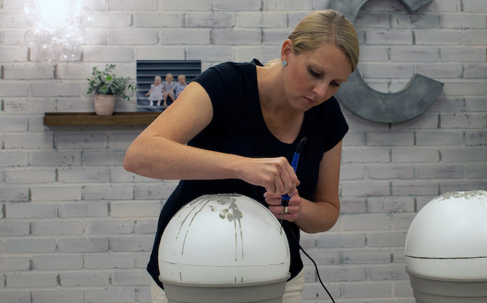 Chelsea Lipford Wolf uses a hot knife to remove foam from a concrete garden sphere