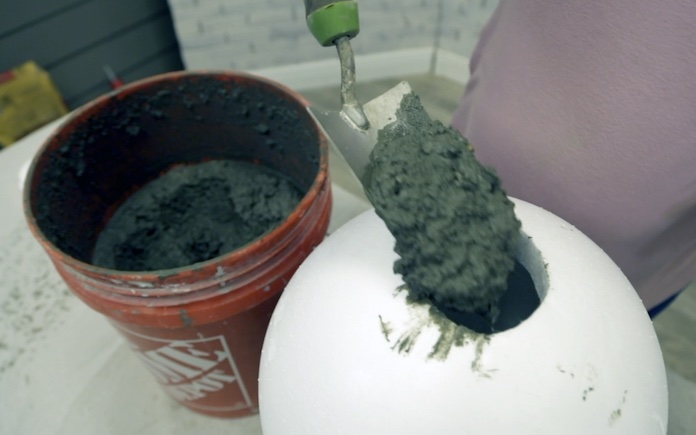 Trowel pouring concrete into a foam ball