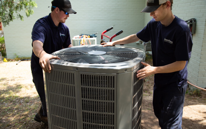 Two workers move to install a home air conditioner