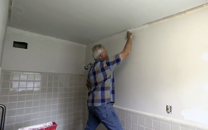 Danny Lipford applies drywall mud to patch holes from ceiling trim.