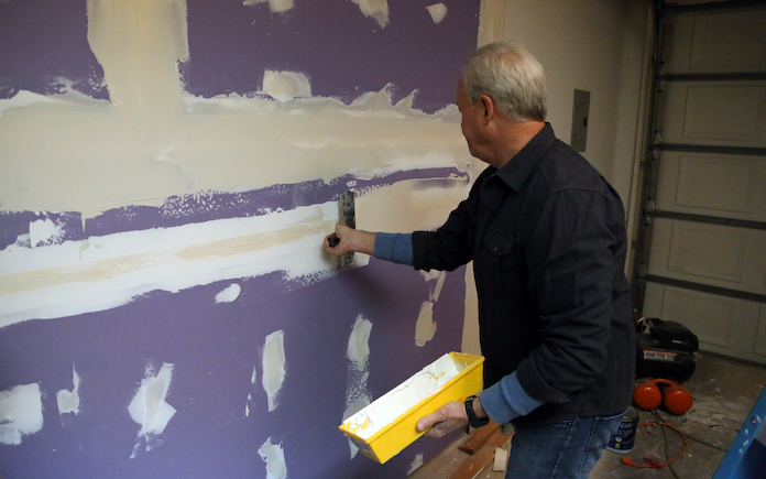 Danny Lipford applies compound compound to drywall in garage