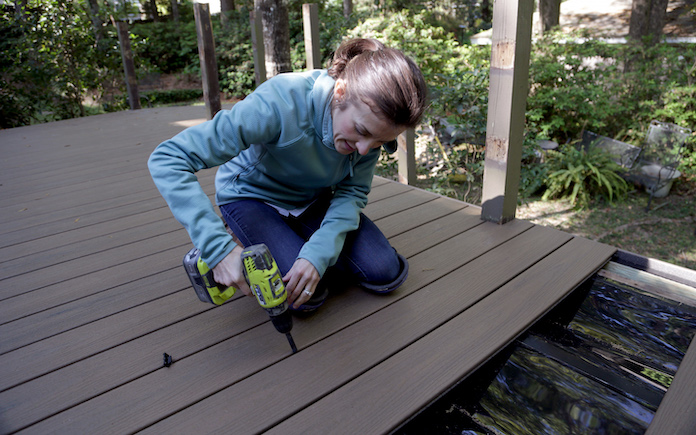 Woman using drill to install Trex Enhance composite wood decking