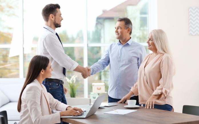 Couple shaking hands with insurance agent in office