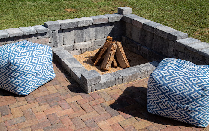 Square fire pit in the corner of a paver patio