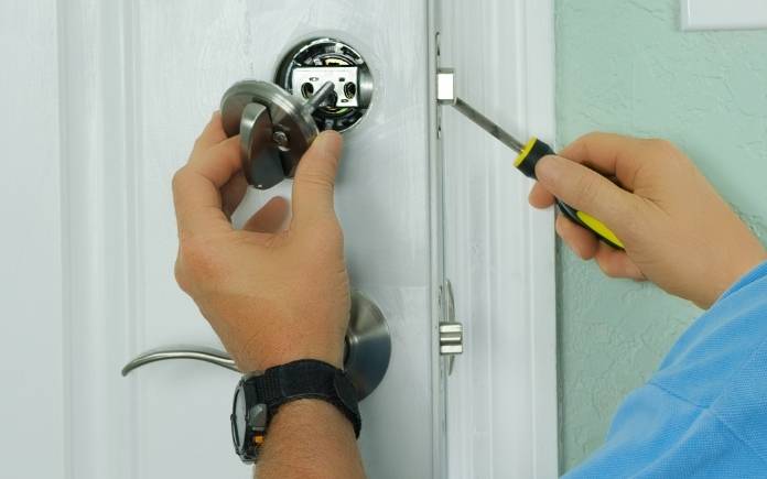 A professional locksmith installing or repairing a new deadbolt lock on a house door