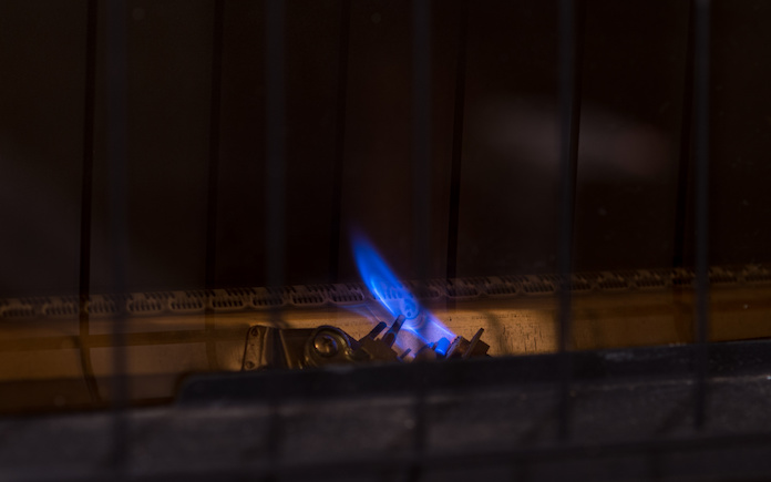 Petite flamme pilote pour réchauffeur de fournaise au gaz. Flamme bleue constante pour l'allumage des brûleurs principaux, derrière la grille de sécurité. Chambre pour copie.
